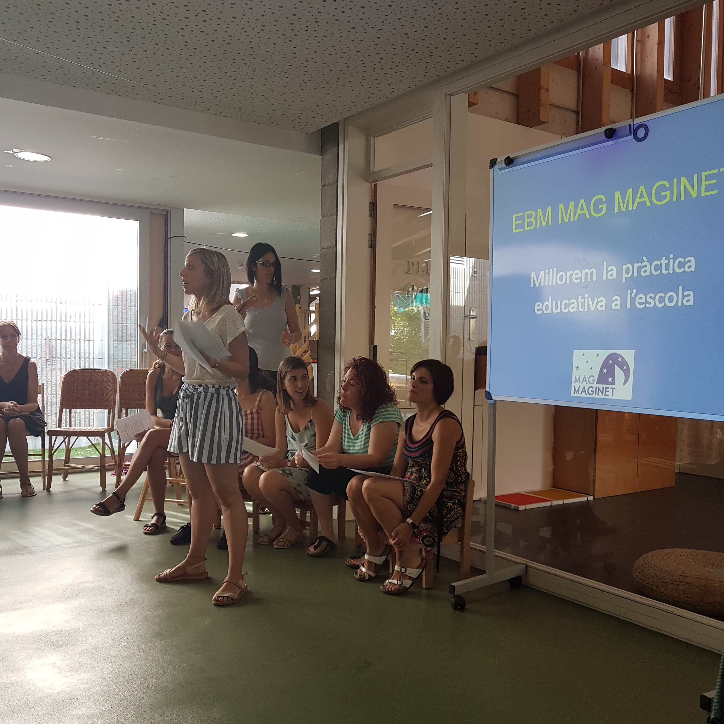 Equip educatiu de Mag Maginet exposant el seu projecte amb presentació sobre pissarra blanca